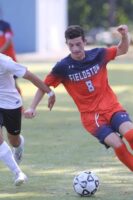 Boys varsity soccer player dribbles away from opponent