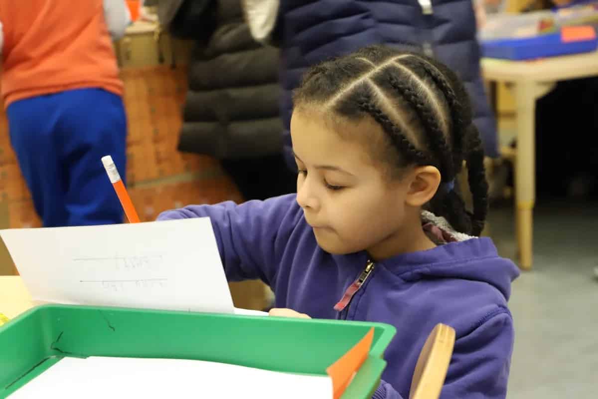 Student addresses envelope at desk