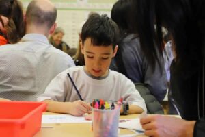 Student addresses envelope at desk