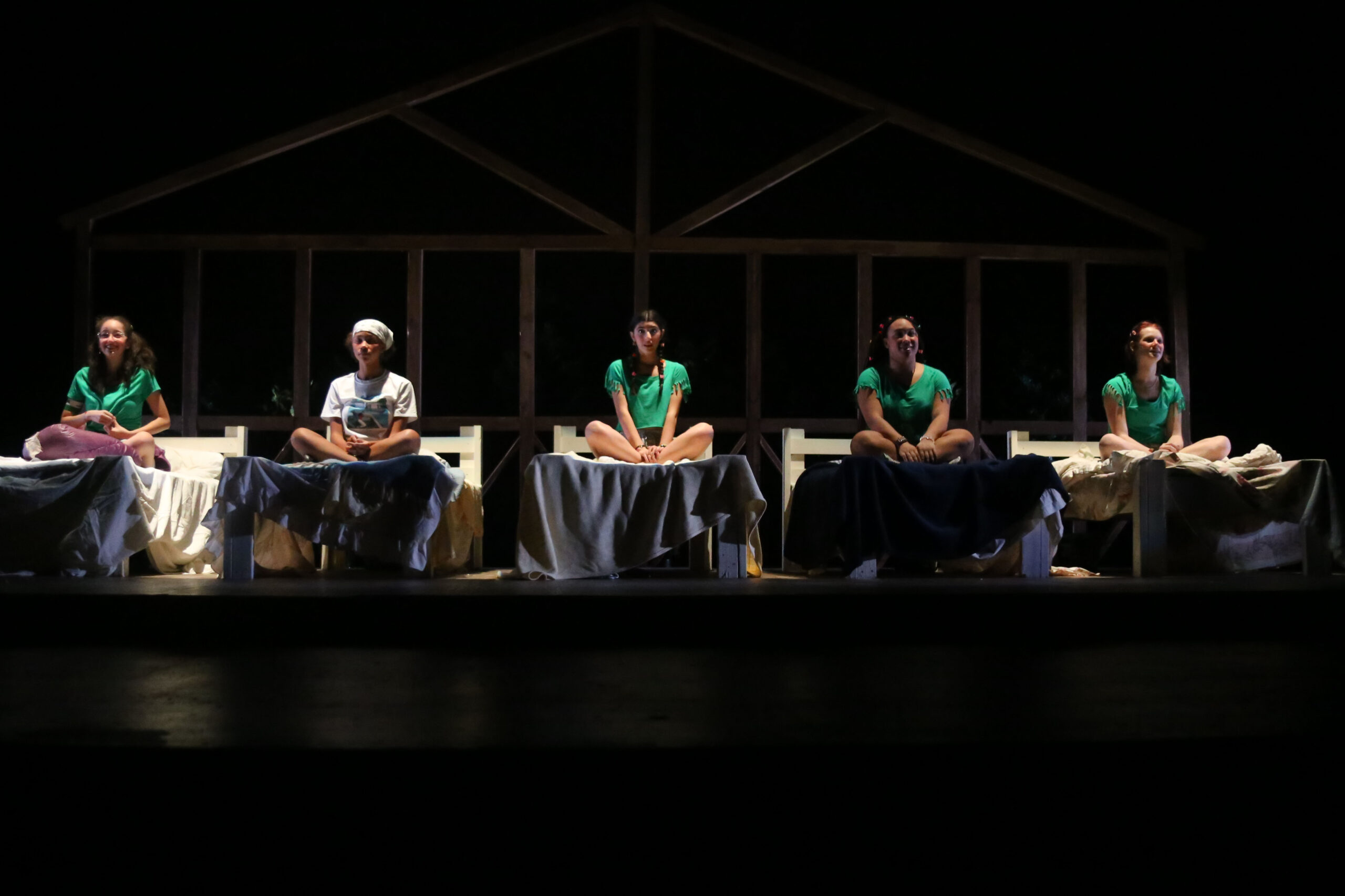 Fieldston Upper students sitting on a row of beds on stage during the fall drama theatre production at the Ethical Culture Fieldston School
