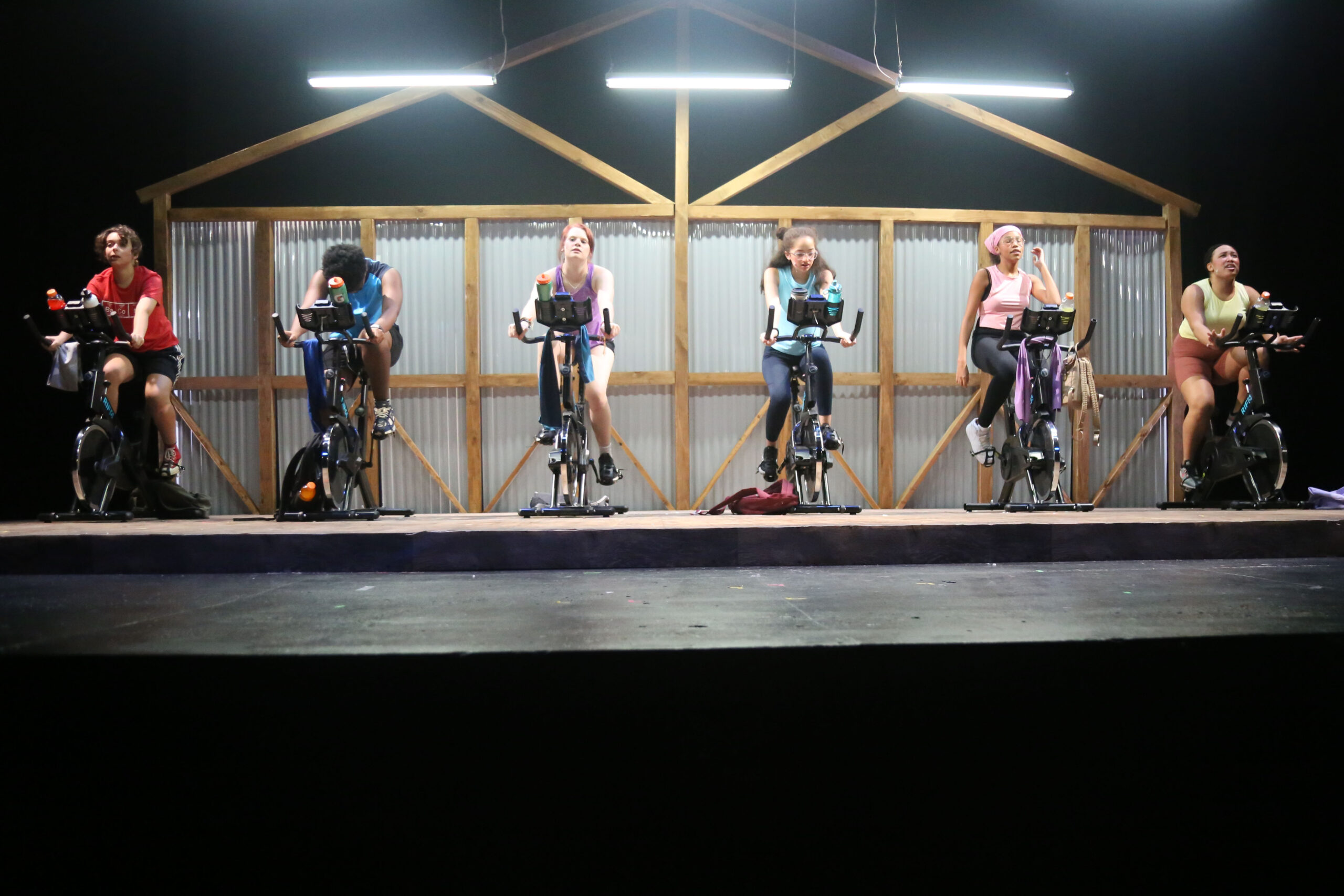 Fieldston Upper students riding bikes on stage during the fall drama theatre production at the Ethical Culture Fieldston School