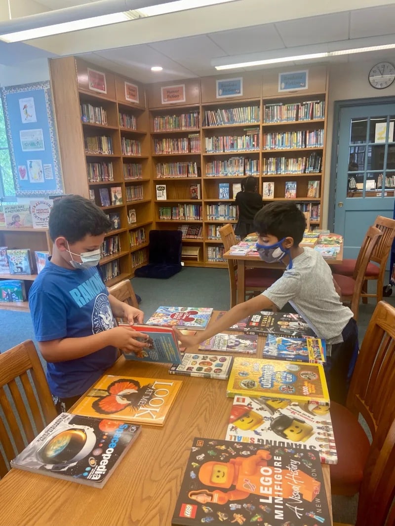 Students look through books on table in library