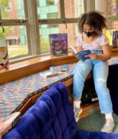 Student sits in library nook reading book