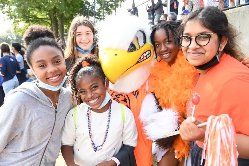 Group of students pose and smile with eagle mascot at homecoming