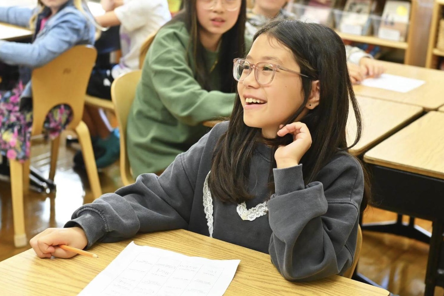 An Ethical Culture Fieldston School student smiles while sitting at a desk