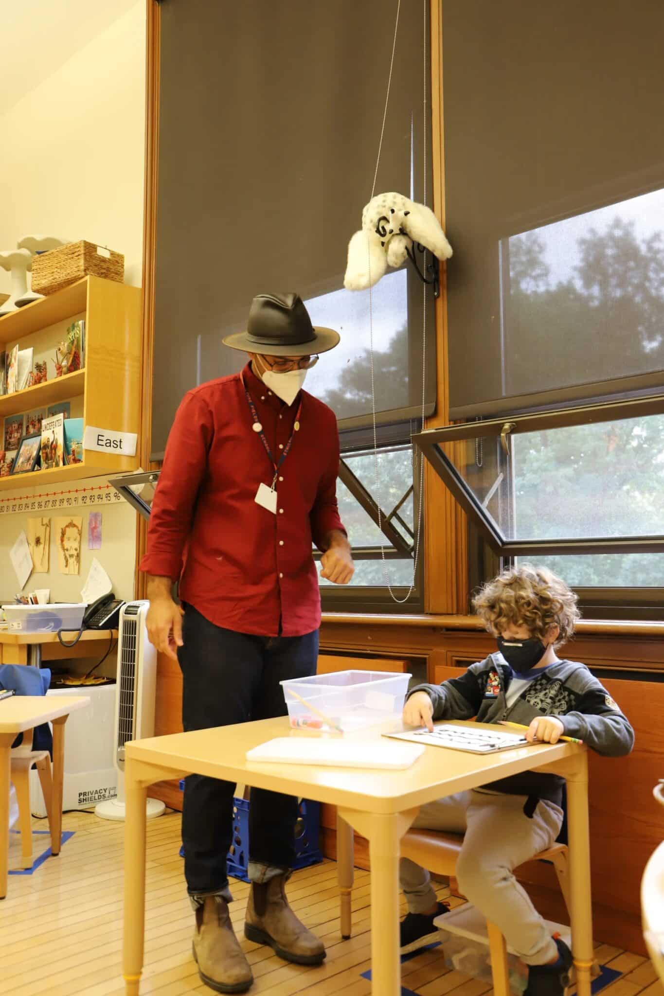 Teacher instructs teacher who sits at their desk