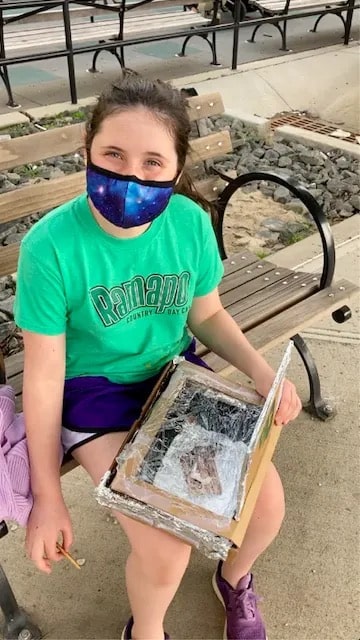 student poses with solar oven outside