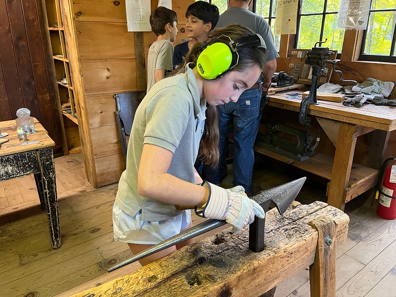 Ethical Culture student works in blacksmith shop on Ashokan outdoor learning trip.