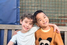Ethical Culture students smile on the rooftop playground bench.