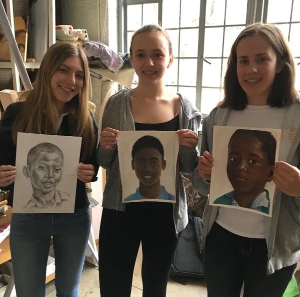 three students pose with their artistic portraits