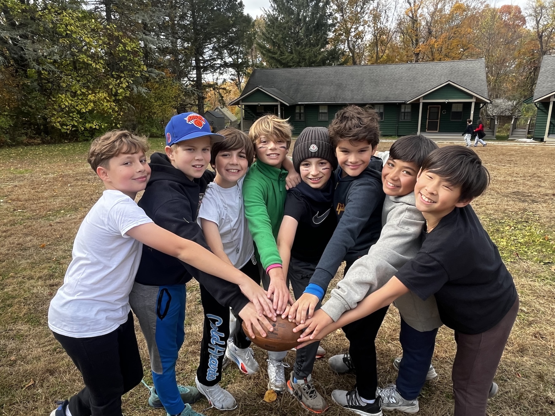 A group of smiling 5th Grade students hold a football during their Outdoor Classroom trip