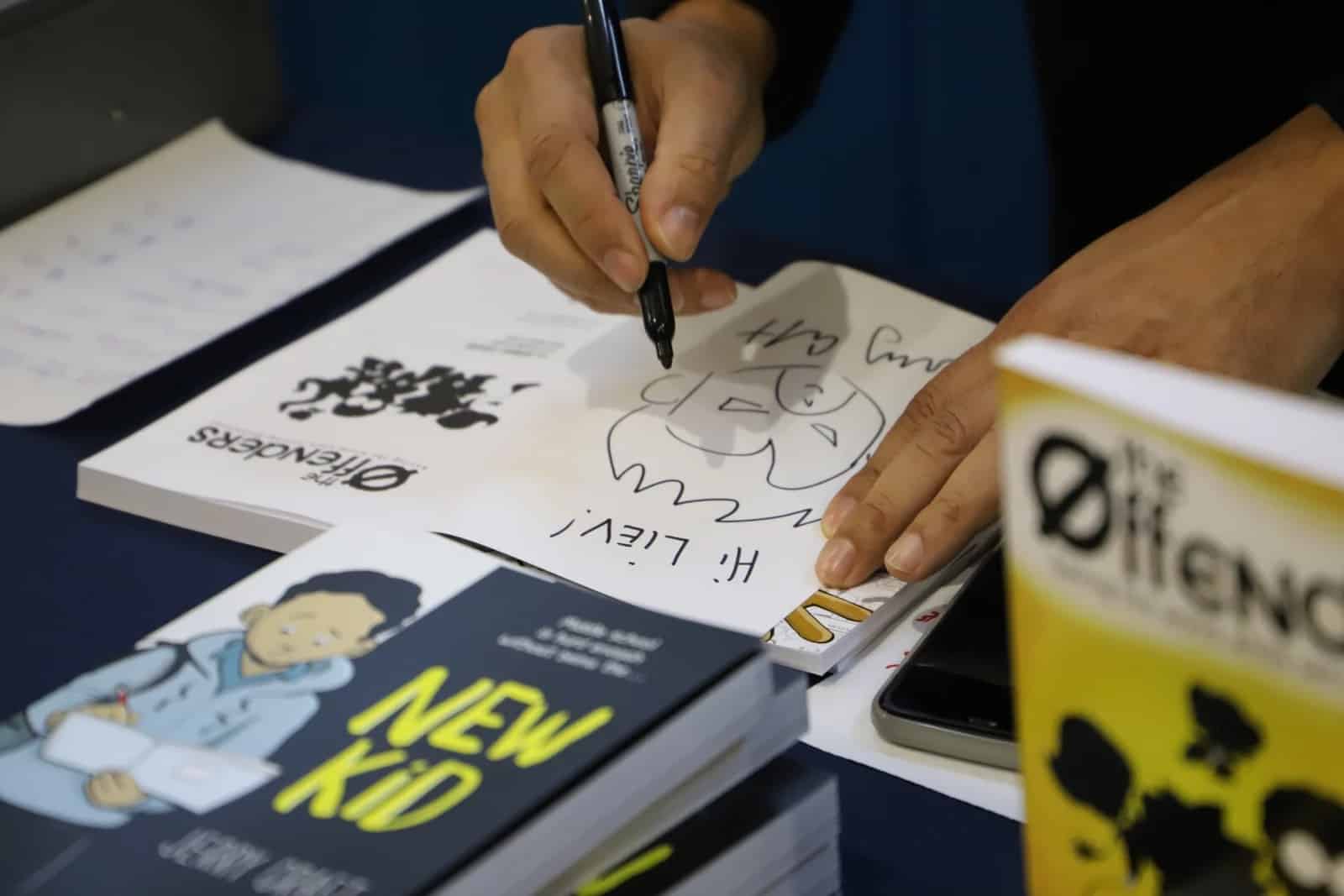 Close up of Craft's hands as he autographs book for student