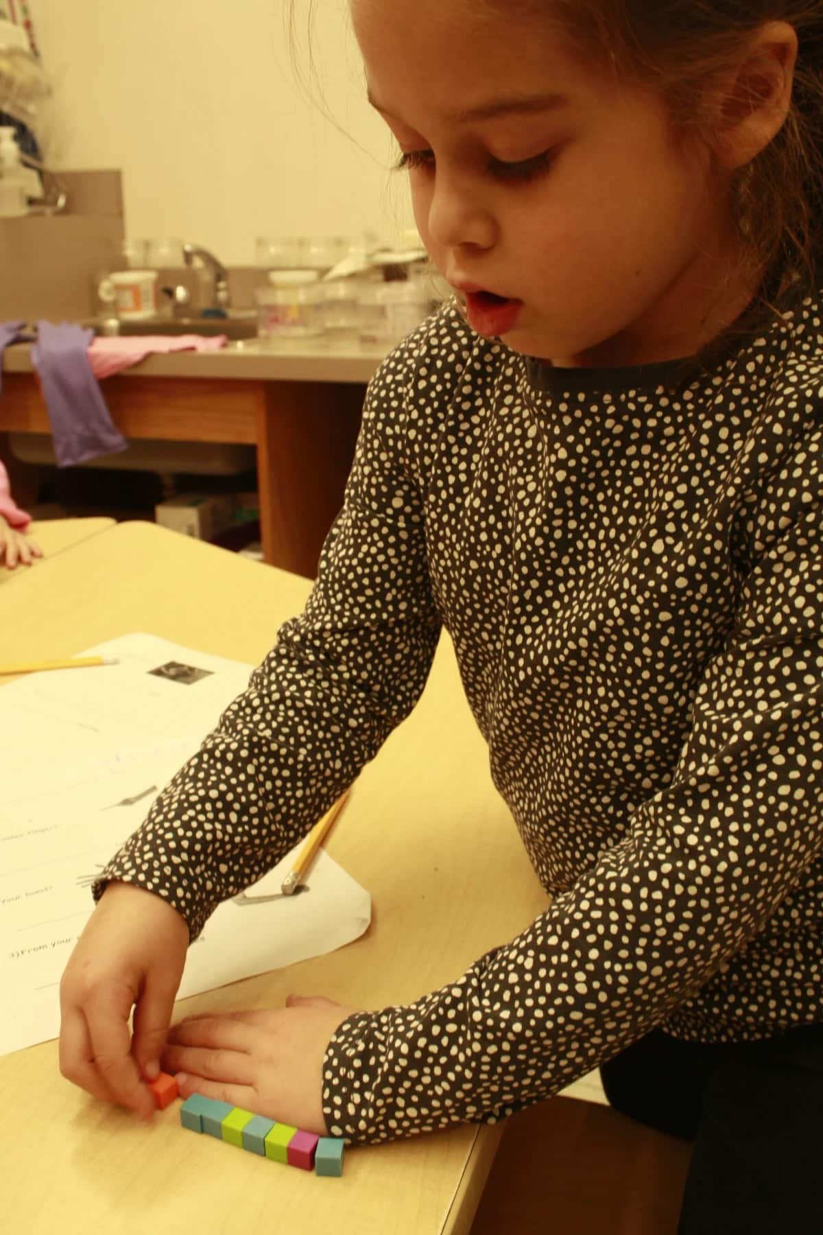 Student measure their hand using cubes