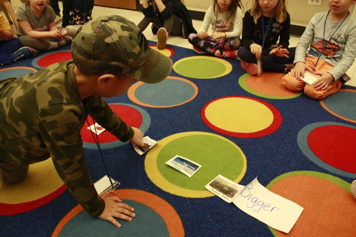 Student organizes items by size on carpet