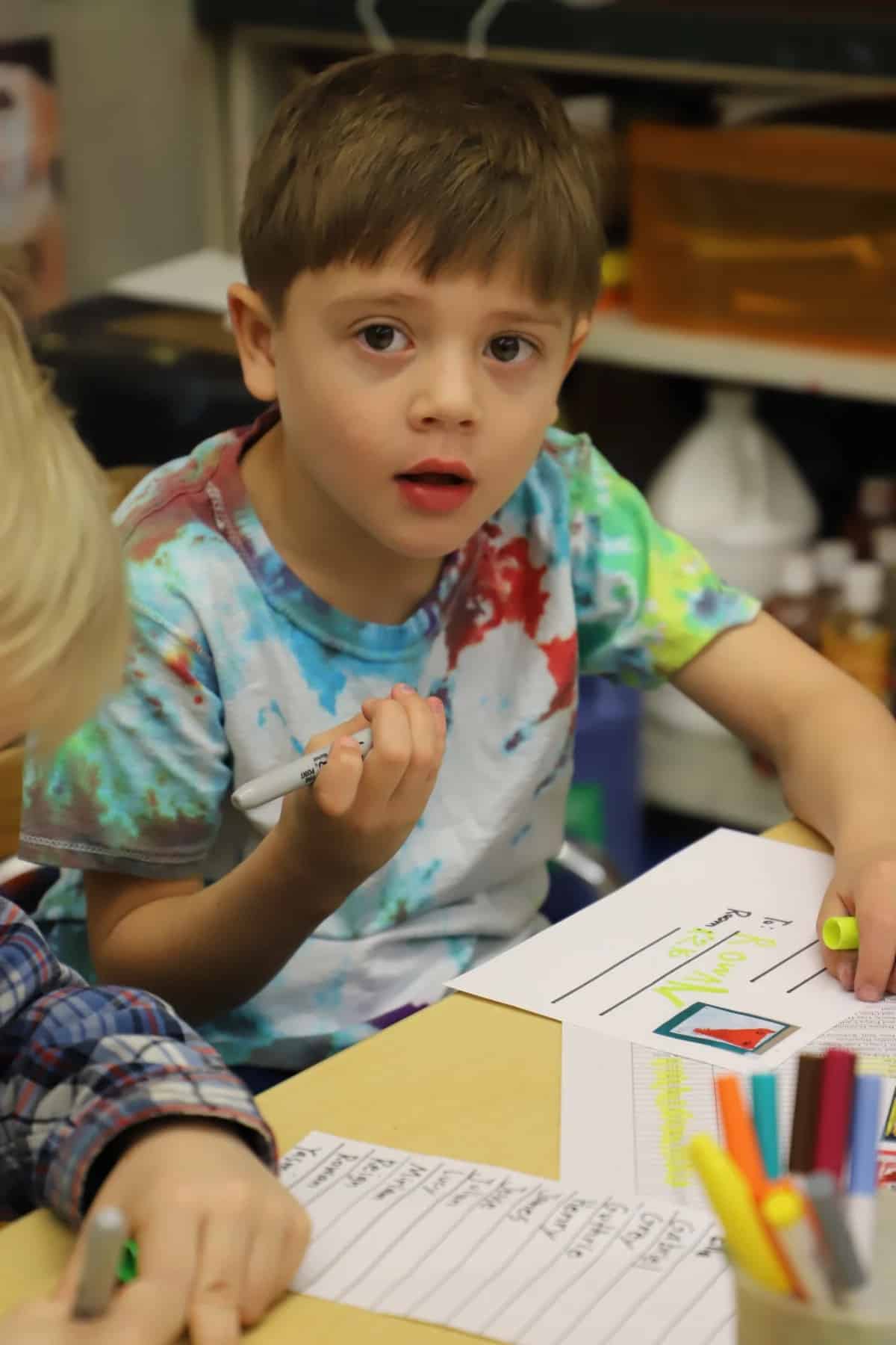 Student looks at camera as he works on stamps